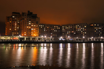 Fototapeta na wymiar City embankment at night. Lights in the windows of apartments and lanterns. Winter is coming.