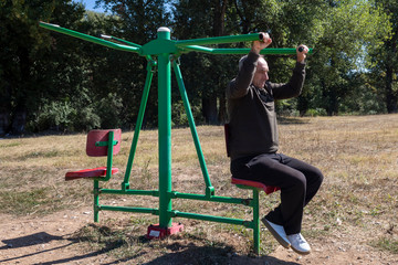 Middle Age Man Trying To Exercise For The First Time After Many Years in Outdoor Gym