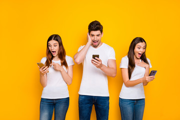 Portrait of three nice-looking attractive lovely charming cheerful cheery stunned wondered person using wi-fi connection speed 5g app isolated over bright vivid shine yellow background