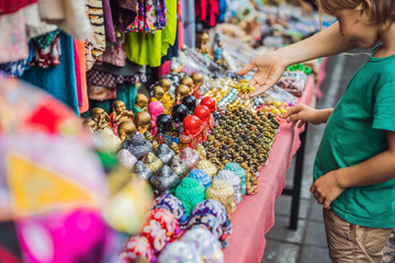 Mom and son travelers choose souvenirs in the market at Ubud in Bali, Indonesia