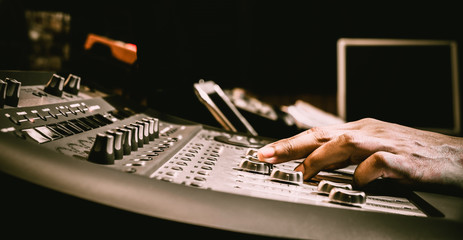 sound engineer hand adjusting audio level on digital mixing console fader in recording,...