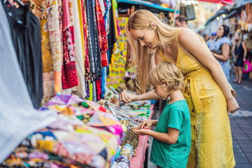 Mom and son travelers choose souvenirs in the market at Ubud in Bali, Indonesia