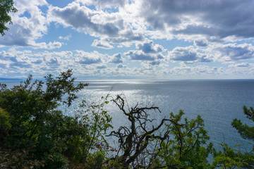 Beautiful view of the Black Sea from top of the hill of the green rain forest. Blue sky with clouds. Sun light reflection.