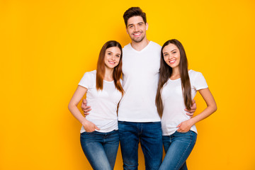 Portrait of charming fellows looking at camera with beaming smile wearing white t-shirt denim jeans isolated over yellow background