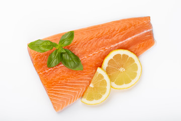 Fresh raw salmon fillets with herbs and lemon isolated on white background.