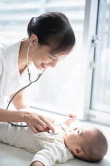 Female nurse examining baby with stethoscope