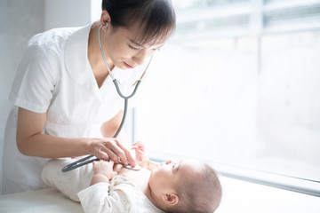Female nurse examining baby with stethoscope