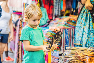 Boy at a market in Ubud, Bali. Typical souvenir shop selling souvenirs and handicrafts of Bali at the famous Ubud Market, Indonesia. Balinese market. Souvenirs of wood and crafts of local residents