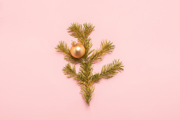 Branch spruce balls of gold color on a pink background. Holiday concept. Flat layout. Copy space.