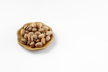 wood plate of salted pistachio nuts isolated on white background.