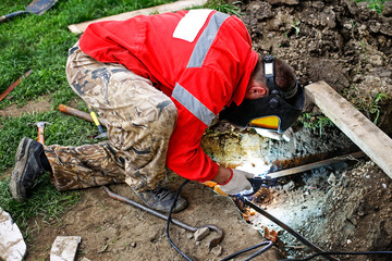 Man in welding mask performing weld construction. Welder constructing earth grounding system....