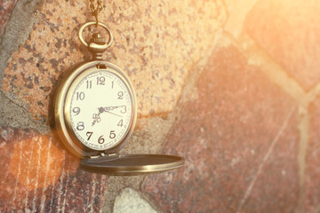 Vintage golden pocket watch on rock background, time concept. Toned photo, instagram effect