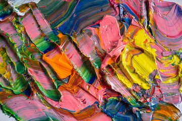 Artistic background. Different bright colors of oil paints are mixed on a palette close-up.