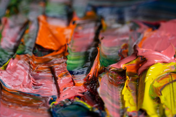 Artistic background. Different bright colors of oil paints are mixed on a palette close-up.