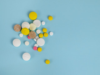 A bunch of multicolored tablets on a blue background. Top view. The concept of medicine and healthcare.
