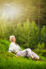 Portrait of Relaxing Senior Woman Resting in Forest Outdoors.