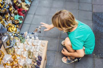 Boy at a market in Ubud, Bali. Typical souvenir shop selling souvenirs and handicrafts of Bali at the famous Ubud Market, Indonesia. Balinese market. Souvenirs of wood and crafts of local residents