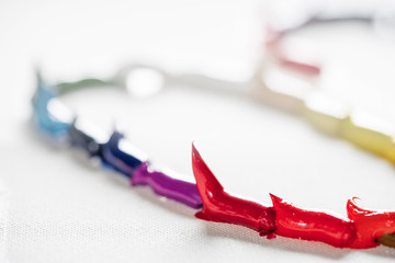 Different bright colors of oil paints are mixed on a palette close-up.