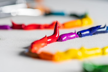 Different bright colors of oil paints are mixed on a palette close-up.