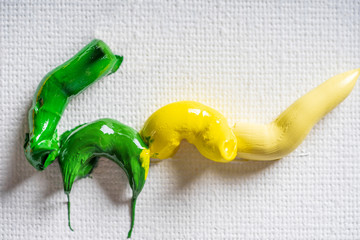 Different bright colors of oil paints are mixed on a palette close-up.