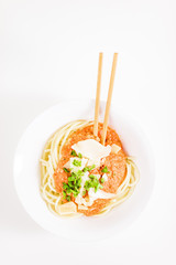 Italian pasta with chopsticks, tomato sauce, parmesan cheese, fresh oregano and basil - on white background.