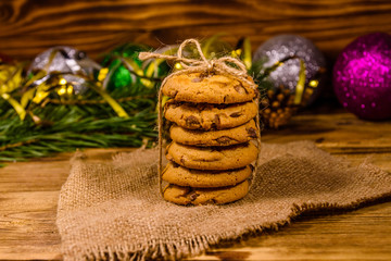 Stack of the chocolate chip cookies on sackcloth in front of christmas decorations