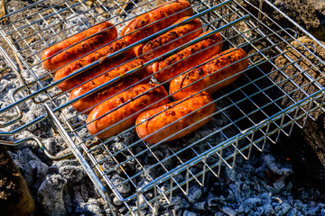 Sausages cooking in a barbecue grill on campfire