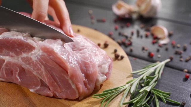 The chef cuts raw meat with the knife in Slow Motion