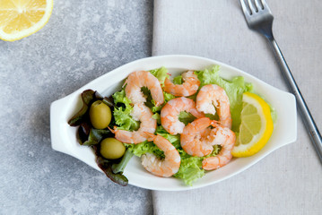Fresh shrimps with olives, lemon and lettuce leaves, top view