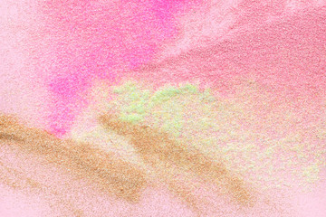 Many multi-colored spangles are scattered on a pink background. View from above. Place for text.