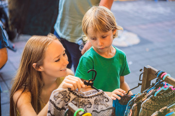 Mom and son travelers choose souvenirs in the market at Ubud in Bali, Indonesia