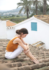 Fototapeta na wymiar Sad woman sitting on top of a roof, thinking about her problems