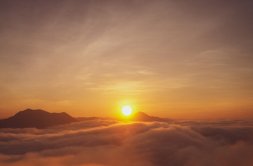 In the early morning, the small sun of orange gradually shone of beautiful golden light amidst a lot of white mist on the high mountains in Phu Thok, Loei Province, Thailand.