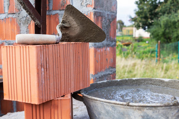 Trowel in the mortar, a container of cement, construction concept.