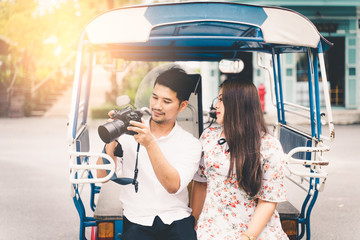 Happy Asian couple are smiling and looking dslr camera. attractive smiling man and woman traveling together.