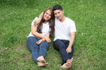 Asian young couples wearing white T-shirts are relaxing and sitting in garden.