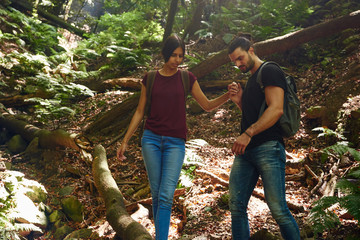 Naklejka na ściany i meble Couple negotiating a steep path over a fallen tree