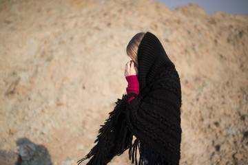 teen girl with blond hair in a hood in the desert