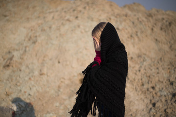 teen girl with blond hair in a hood in the desert