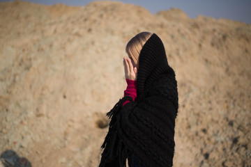 teen girl with blond hair in a hood in the desert