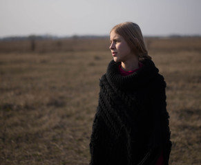 teen girl with blond hair in a hood in the desert