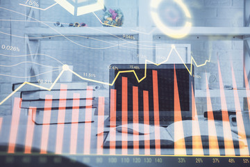 Stock market graph on background with desk and personal computer. Multi exposure. Concept of financial analysis.