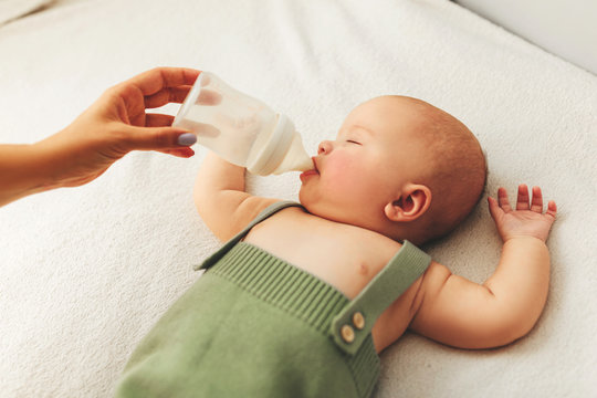 Nursing a baby. Feeding the newborn with formula in a bottle. Breastfeeding problems. Mother s love and warmth.