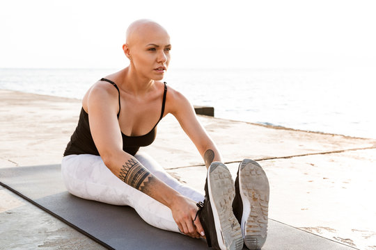 Image of confident bald woman doing exercises on mat while working out