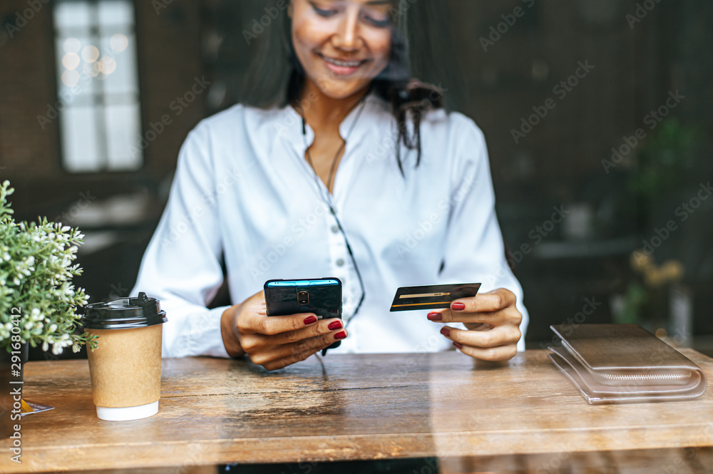 Wall mural Pay for goods by credit card through a smartphone in a coffee shop.