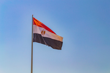 Flag of Egypt on flagpole against clear blue sky