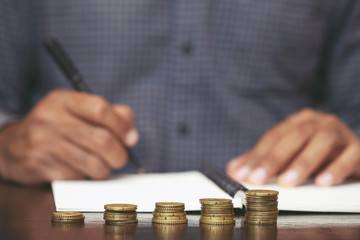 close up hand young man are sitting using pen writing Record Lecture note pad into the book on the table wood.