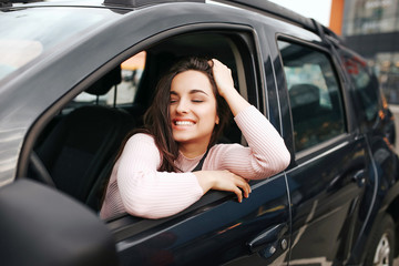 Picture of nice positive woman in car. Posing and smile. Sitting alone in black car.