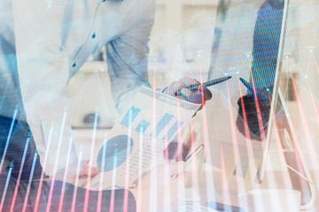 Multi exposure of chart with man typing on computer in office on background. Concept of hard work.