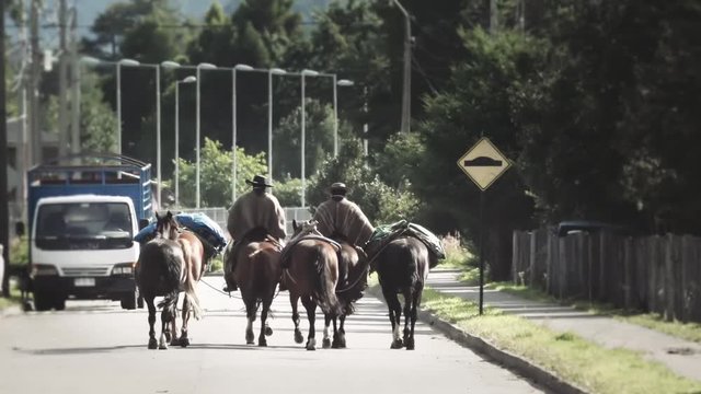Three horsemen riding on the street of the city. Typical Gauchos moving a herd of horses from the highway. Slow motion